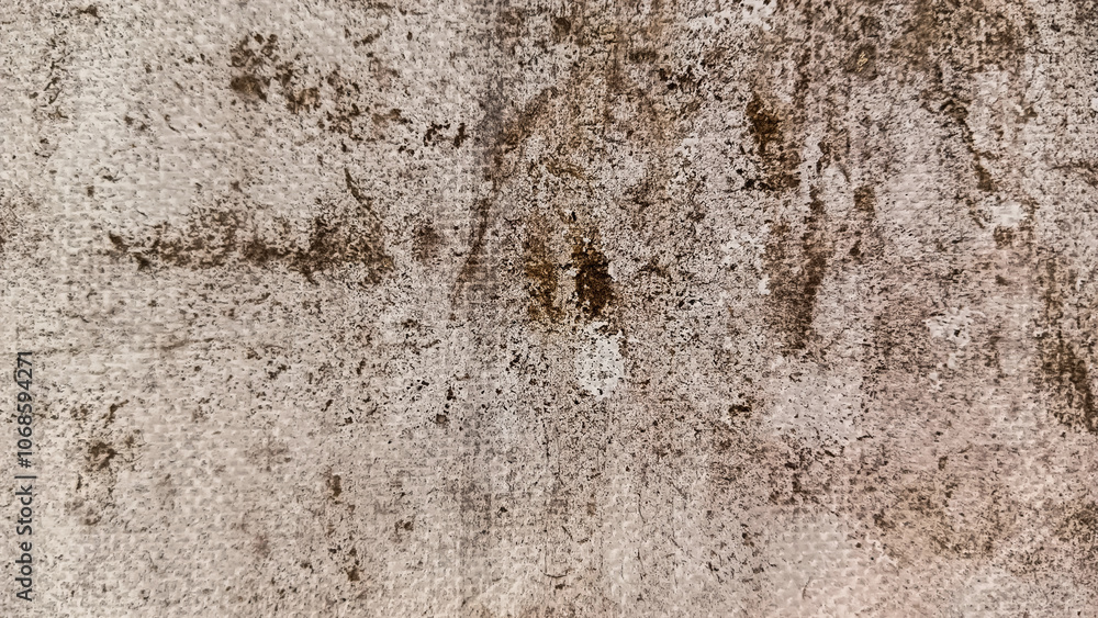 Detailed view of a rough, weathered surface featuring brown stains and irregular patterns, creating an abstract, aged appearance.