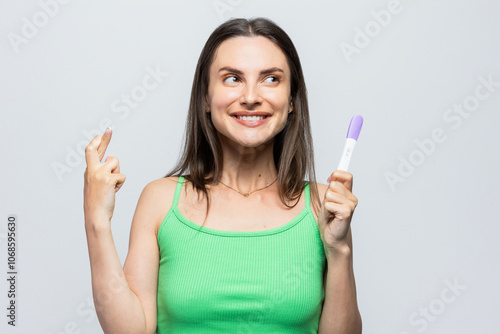 Young woman hoping the pregnancy test will be positive. On white background. photo