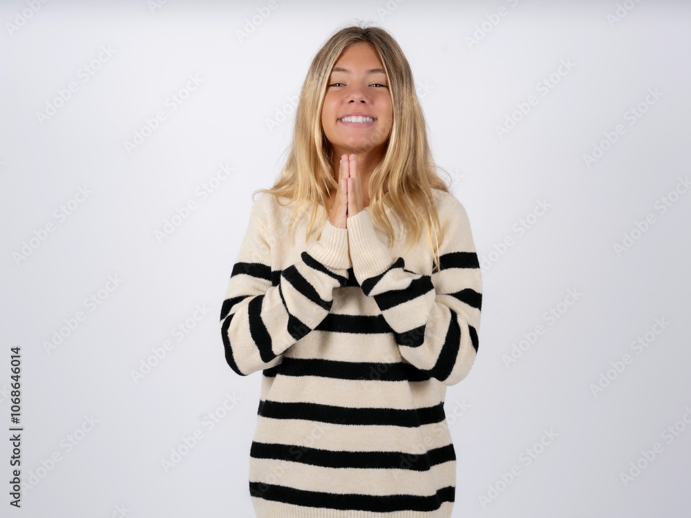caucasian teen girl wearing striped knitted sweater over white praying with hands together asking for forgiveness smiling confident. caucasian teen girl wearing striped knitted sweater over white praying with hands together asking for forgiveness smiling confident.