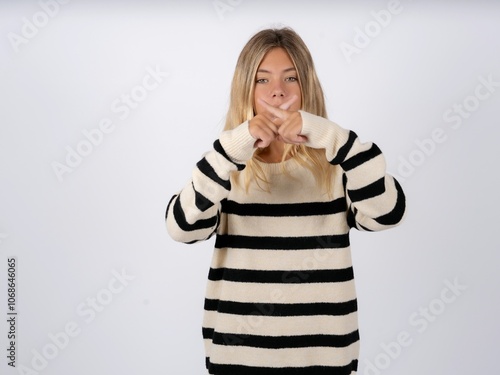 caucasian teen girl wearing striped knitted sweater over white Has rejection angry expression crossing fingers doing negative sign. photo