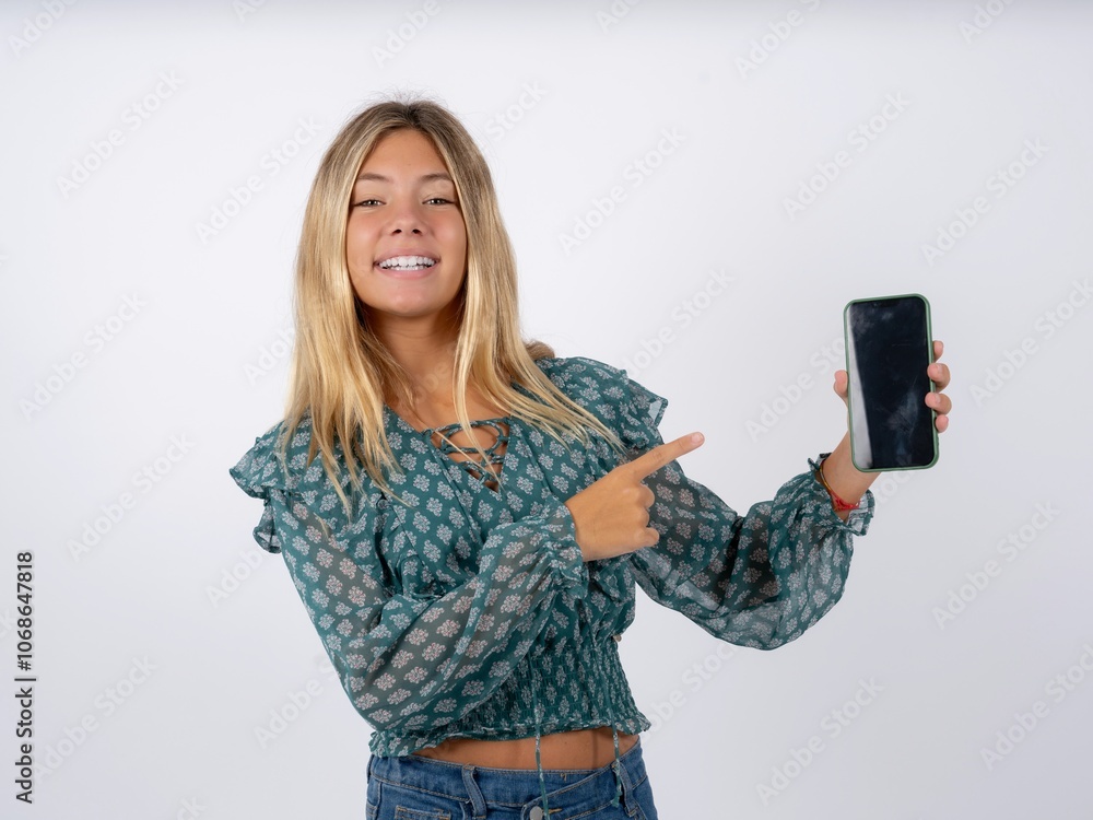Attractive cheerful caucasian teen girl wearing green dress over white holding in hands cell showing black screen Attractive cheerful caucasian teen girl wearing green dress over white holding in hands cell showing black screen