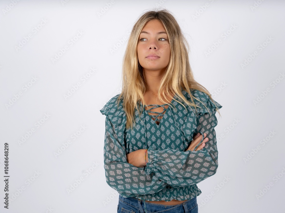 Charming thoughtful caucasian teen girl wearing green dress over white stands with arms folded concentrated somewhere with pensive expression thinks what to do Charming thoughtful caucasian teen girl wearing green dress over white stands with arms folded concentrated somewhere with pensive expression thinks what to do