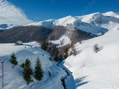 winter landscape with towering snow-capped peaks rising against a cloudless blue sky