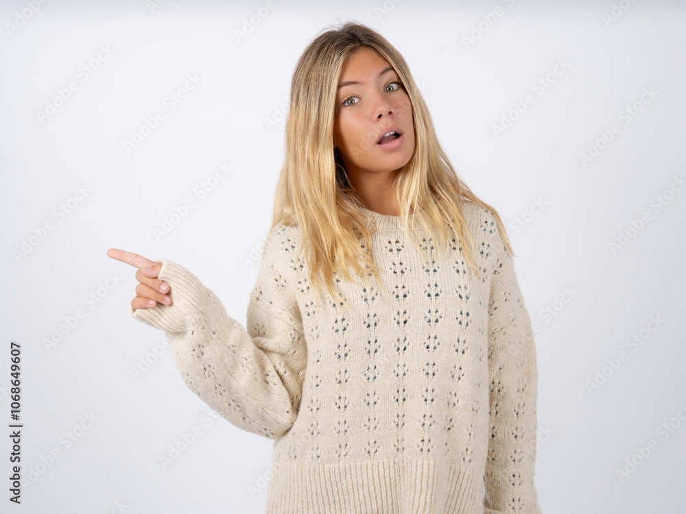 Emotive caucasian teen girl wearing knitted sweater over white keeps jaw dropped from shock demonstrates amazing promo points right on blank space demonstrates big shopping sale. Advertisement Emotive caucasian teen girl wearing knitted sweater over white keeps jaw dropped from shock demonstrates amazing promo points right on blank space demonstrates big shopping sale. Advertisement