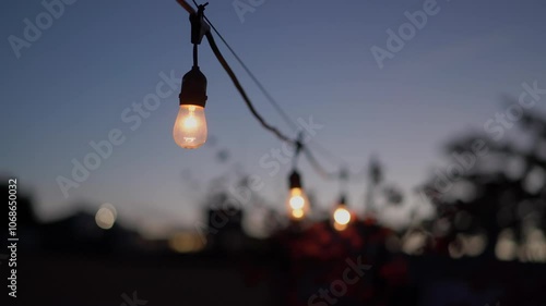 A closeup view of glowing string lights beautifully illuminating the twilight sky, evoking both warmth and tranquility