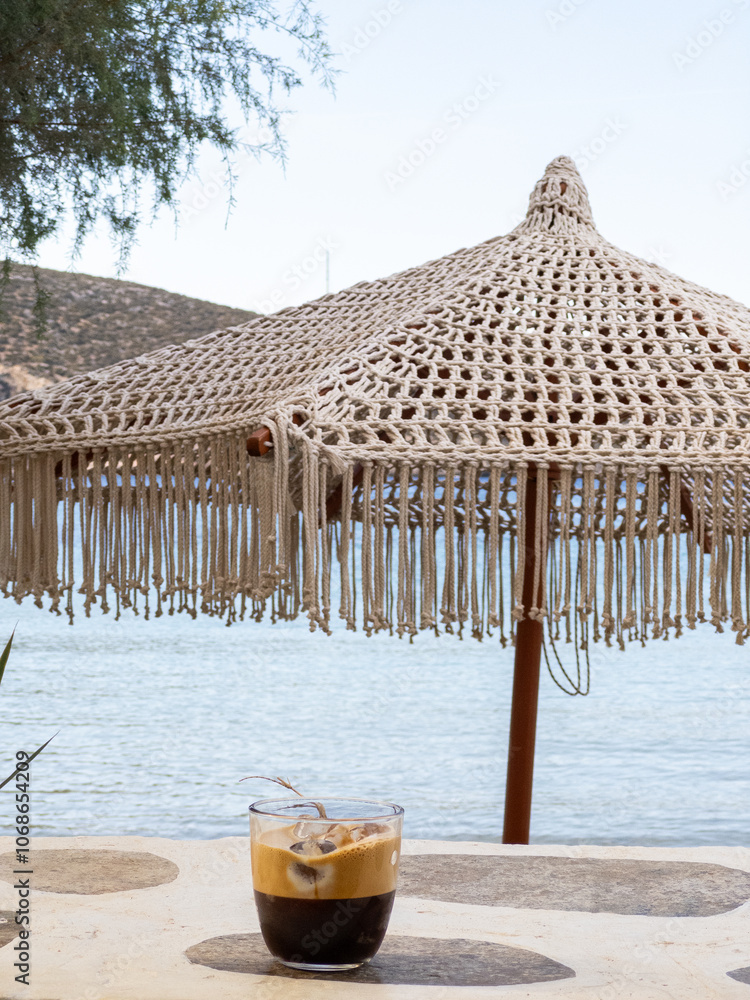 Greek Freddo Espresso under a woven umbrella on Vathi Beach, Sifnos Island