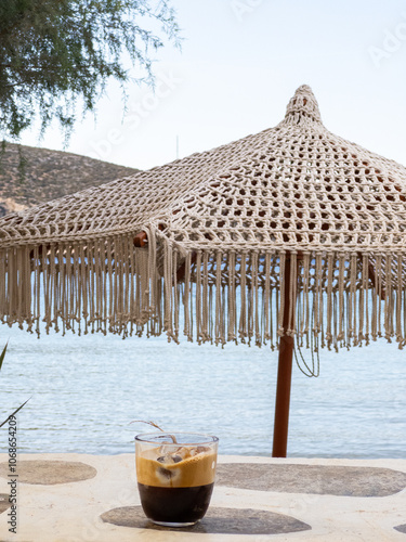 Obraz na płótnie Greek Freddo Espresso under a woven umbrella on Vathi Beach, Sifnos Island w salonie