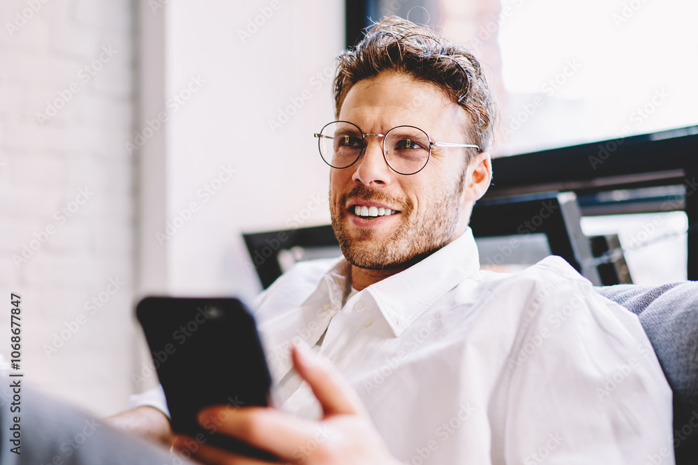 Smiling businessman testing on cellphone on sofa