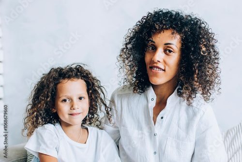 Obraz na plátně Smiling mother with daughter sitting on sofa