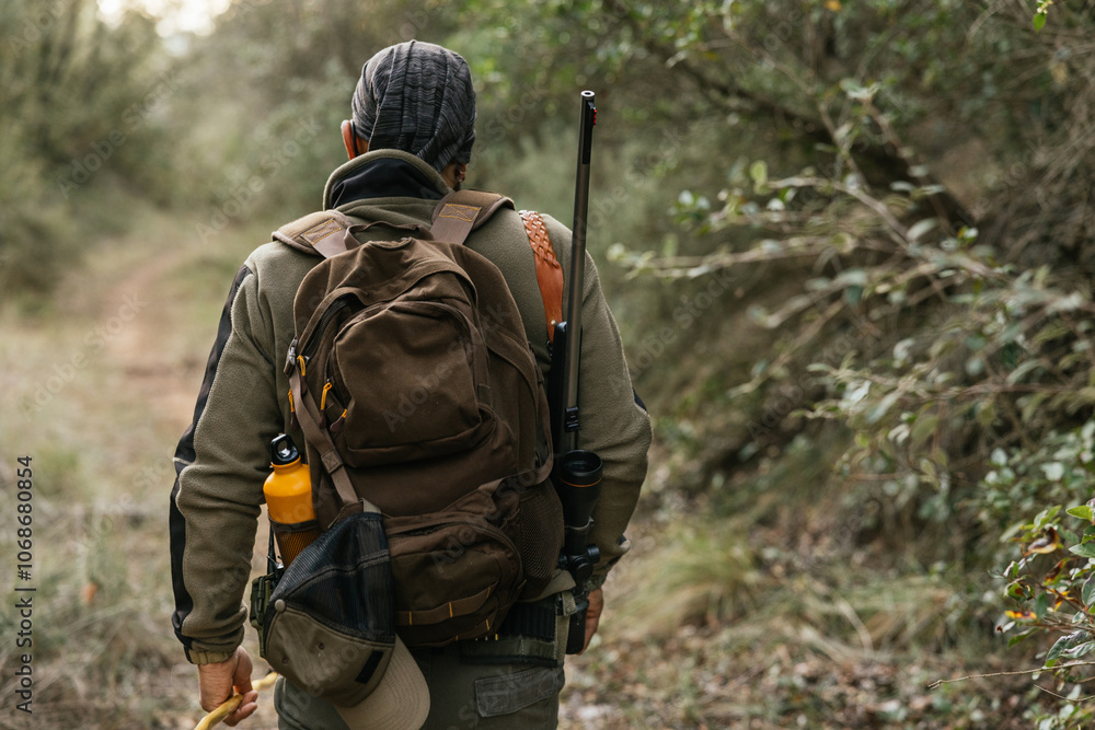 Hunter walking in the woods carrying a rifle and backpack Hunter walking in the woods carrying a rifle and backpack