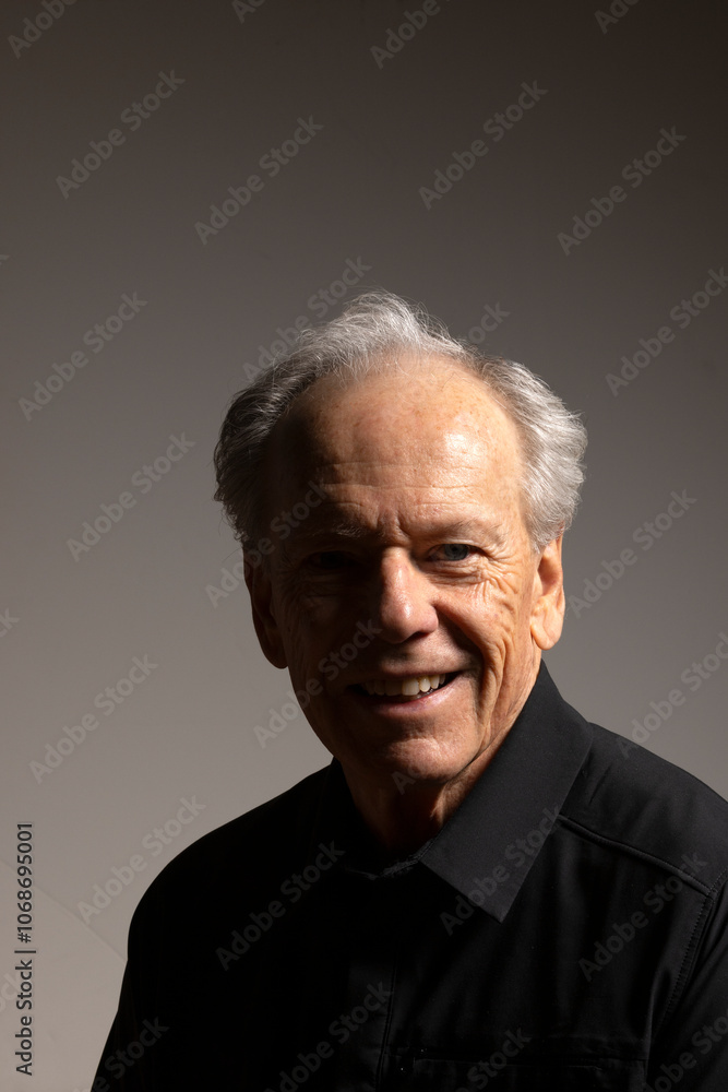 Studio portrait of smiling senior man in black shirt against gray background Studio portrait of smiling senior man in black shirt against gray background