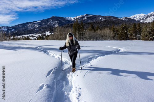 Smiling woman snowshoeing in winter landscape