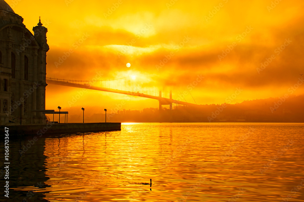 View of the Bosphorus with cormorants on a foggy Ortakoy morning. The 15 July Martyrs Bridge and Ortaköy Mosque in a fog. View of the Bosphorus with cormorants on a foggy Ortakoy morning. The 15 July Martyrs Bridge and Ortaköy Mosque in a fog.