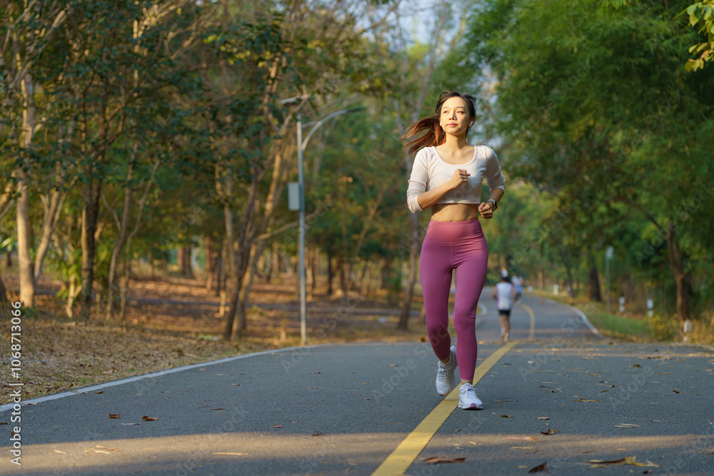 Asian woman jogging in the park smiling happy running and enjoying a healthy outdoor lifestyle. Female jogger. Fitness runner girl in a public park. healthy lifestyle and wellness being a concept. Asian woman jogging in the park smiling happy running and enjoying a healthy outdoor lifestyle. Female jogger. Fitness runner girl in a public park. healthy lifestyle and wellness being a concept.