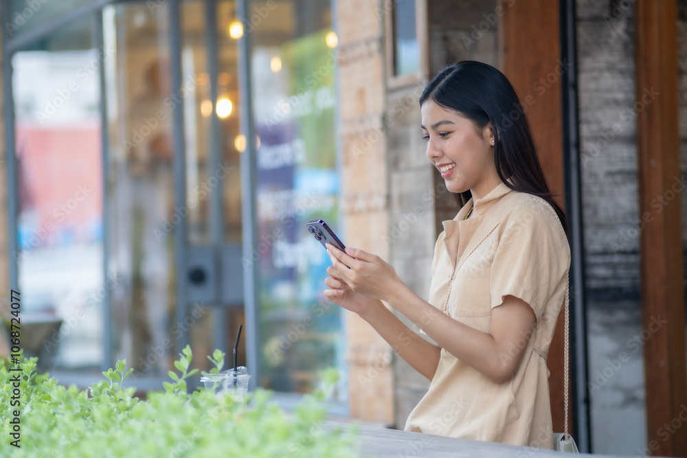 A woman is smiling while looking at her cell phone A woman is smiling while looking at her cell phone