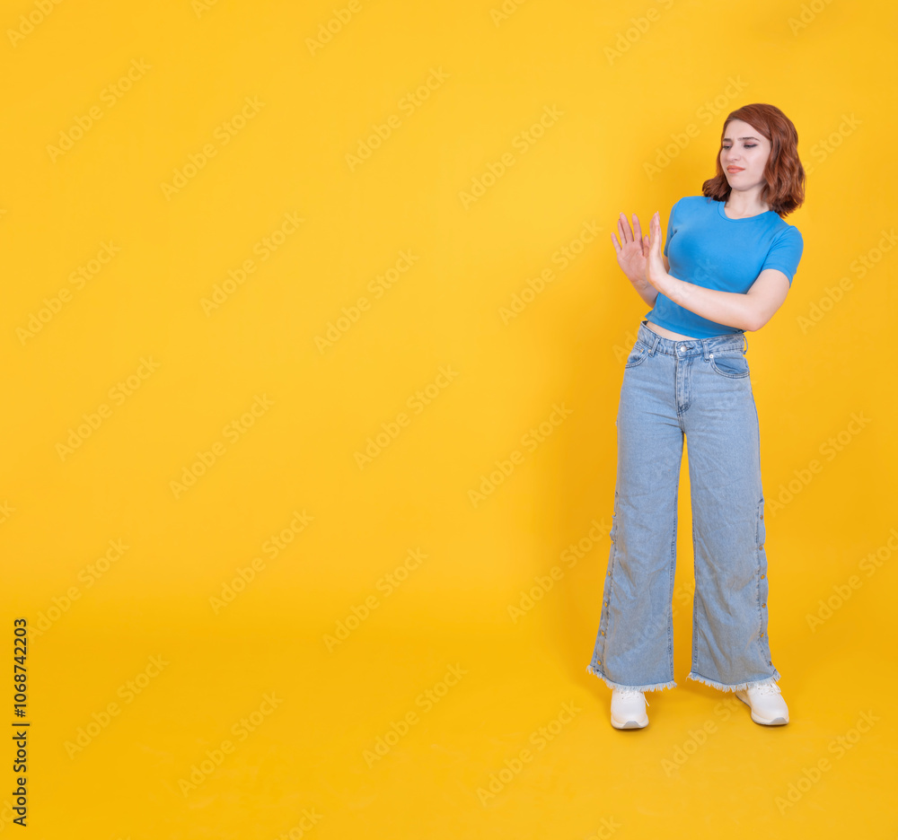 Dissatisfied woman, full body length caucasian 20s dissatisfied woman showing stop sign aside to copy space isolated yellow studio background. Copy space. Disgust face expression design element. Dissatisfied woman, full body length caucasian 20s dissatisfied woman showing stop sign aside to copy space isolated yellow studio background. Copy space. Disgust face expression design element.