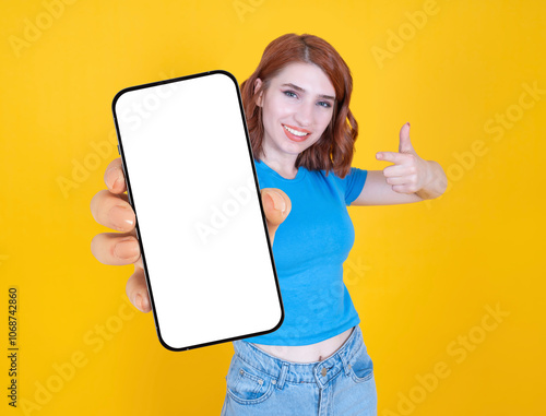 Mobile phone mock up, young fun woman recommend offer new smartphone app or application show camera close up mobile phone mock up with empty blank big touch screen over yellow background show thumb up