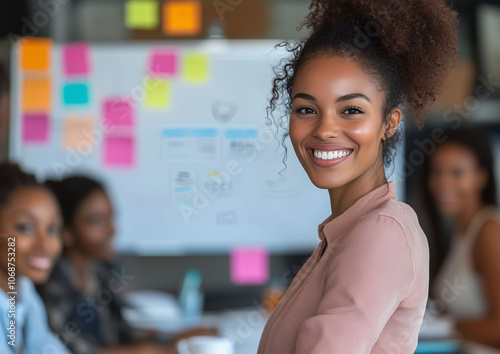 A Black businesswoman smiling at the camera while presenting a project to her executive team, with a board covered in post-its in the background. Working woman, business leadership, empowerment, busin photo