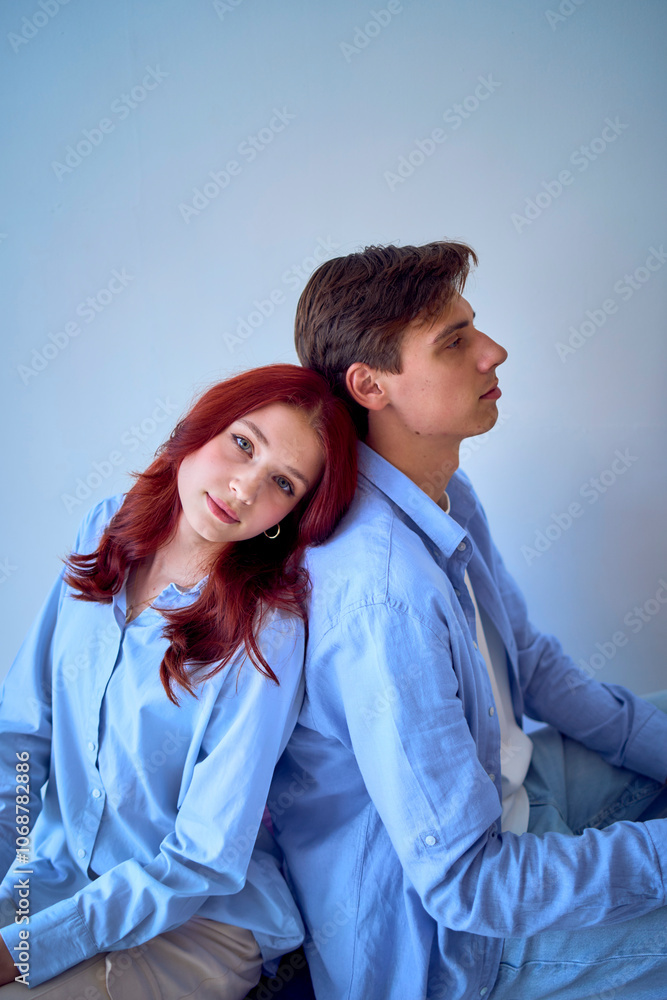 siblings, young adult brother and teenage sister sitting back to back siblings, young adult brother and teenage sister sitting back to back