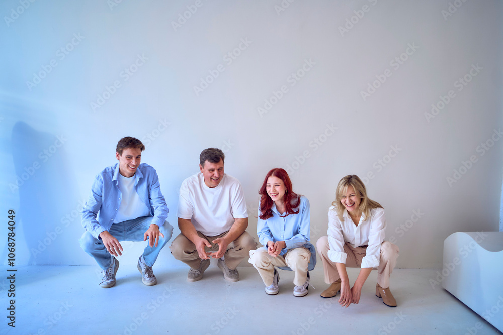 Naklejka premium a family, middle-aged husband and wife, young adult son and teenage daughter, squatting on a white background, studio photo shoot