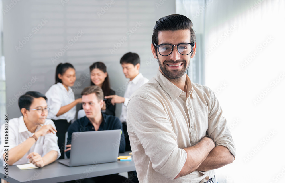 Confidence and happy smiling businessman portrait with background of his colleague and business team working in office. Office worker teamwork and positive workplace concept. Prudent Confidence and happy smiling businessman portrait with background of his colleague and business team working in office. Office worker teamwork and positive workplace concept. Prudent