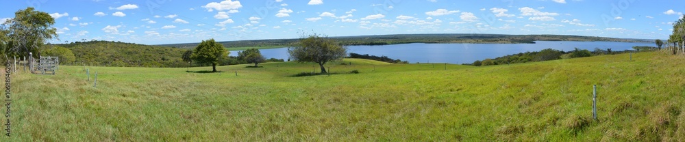 Lush green grass meadow under rural blue sky, grass texture and beautiful lake in the background. Beautiful morning light on green grass farm. the lake of Barragem da Pedra do Cavalo Lush green grass meadow under rural blue sky, grass texture and beautiful lake in the background. Beautiful morning light on green grass farm. the lake of Barragem da Pedra do Cavalo