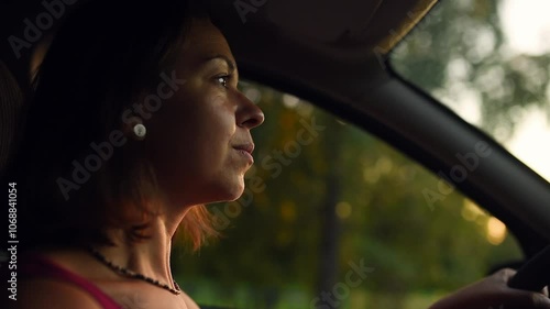 A woman enjoys a relaxed drive through the countryside at sunset, smiling as she leans her arm out the window, capturing a peaceful moment of freedom and serenity