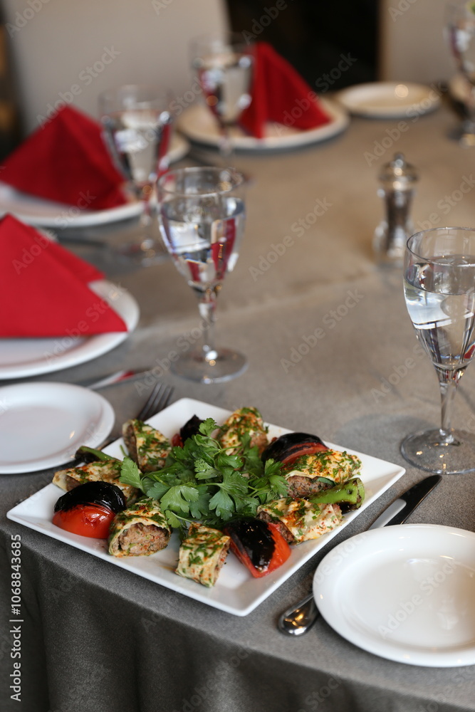 A colorful and gourmet appetizer platter featuring grilled vegetables and meat rolls, perfect for a special occasion or dinner party A colorful and gourmet appetizer platter featuring grilled vegetables and meat rolls, perfect for a special occasion or dinner party