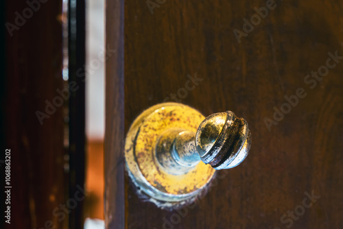 Old brass Door Stopper with brown wooden door and wall. Brass magnetic door stop. Rusty golden Door Stopper or Magnets hold the door. Old classic brass door stopper attached to a dark wooden surface. photo