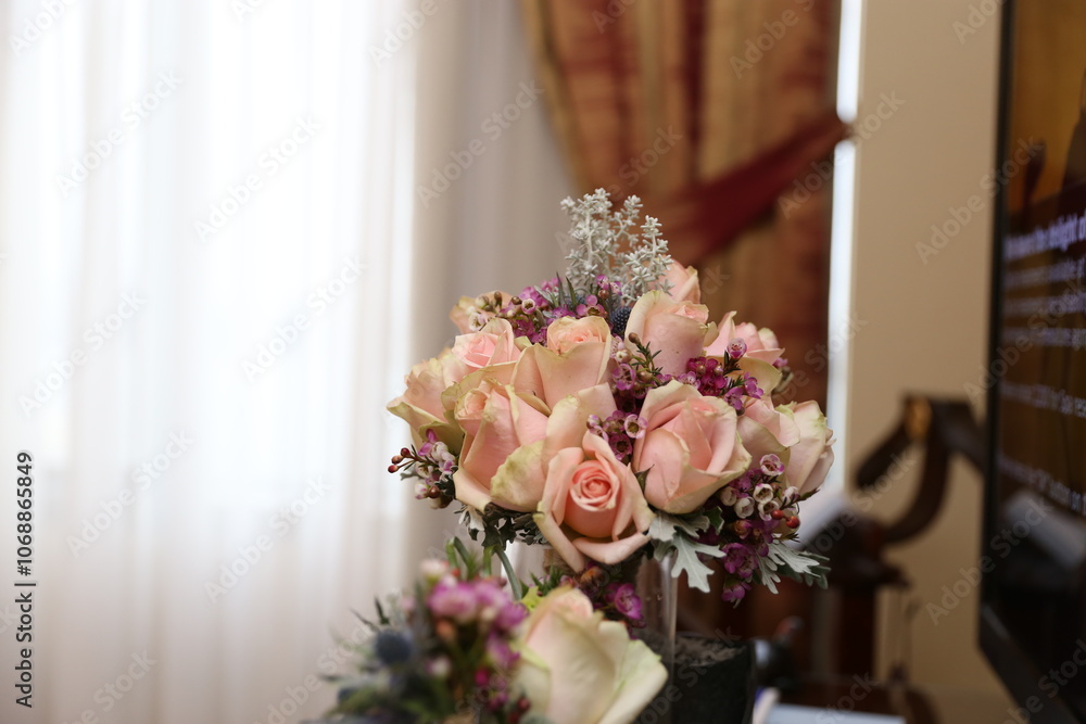A delicate and romantic bridal bouquet with blush pink roses and greenery, resting on a vintage piano