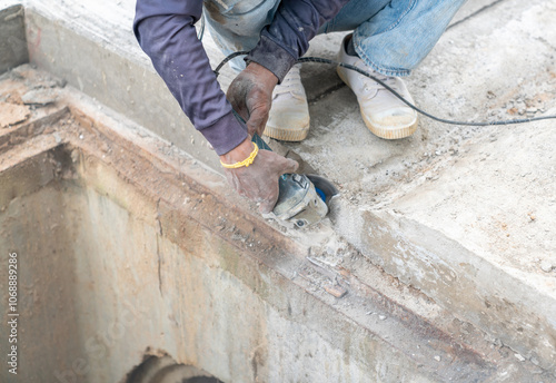 Construction worker cuts with working diamond bladed cut off saw to concrete drainager ditch.