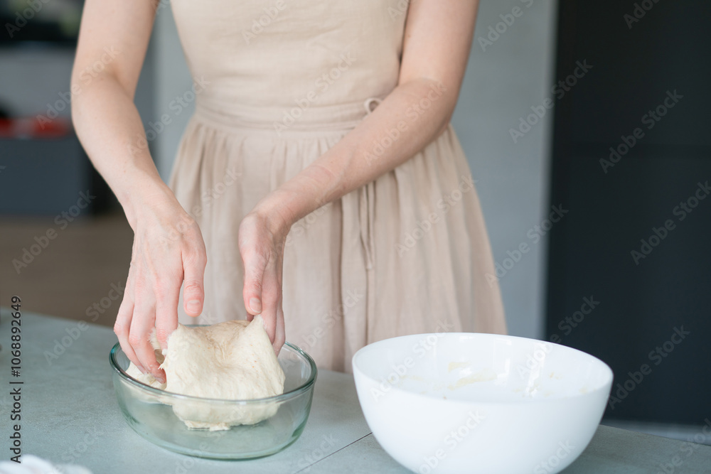 Girl in the kitchen in a beige dress preparing dough Girl in the kitchen in a beige dress preparing dough