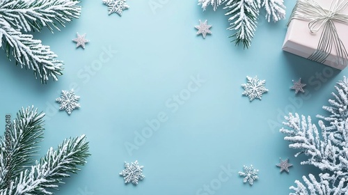 Frosted pine branches, snowflakes, and gift box on blue background