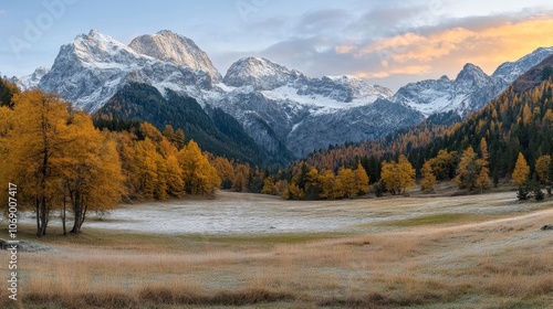 A serene mountain landscape at sunrise, featuring autumn colors and snow-capped peaks.