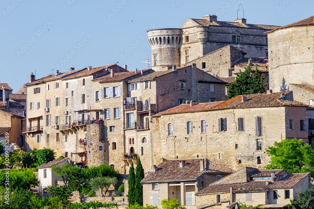 GORDES, PROVENCE, FRANCE: stone facades of luxury holiday homes, warm late afternoon sunlight, with balconies and terracotta roof tiles, detail shot of one of the most beautiful villages in France GORDES, PROVENCE, FRANCE: stone facades of luxury holiday homes, warm late afternoon sunlight, with balconies and terracotta roof tiles, detail shot of one of the most beautiful villages in France