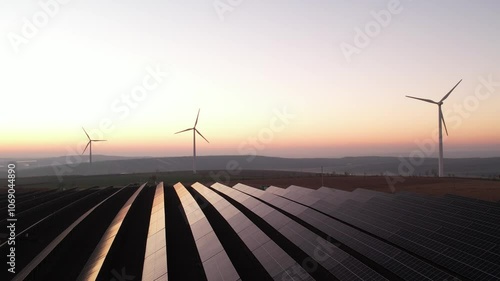 Solar panels park and wind turbines at sunset.Windmill turbines generating green energy electric.Green energy reduce carbon emissions and makes earth cleaner and more ecological.	
