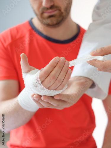 doctor bandaging the hand of a sport man after an accident