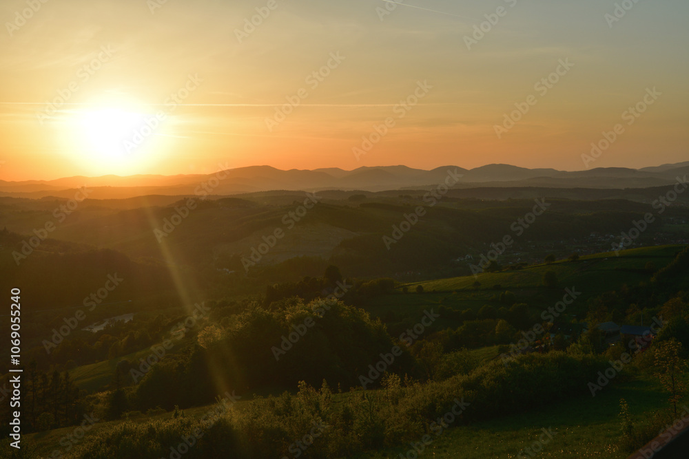 The sunset and its rays dazzle the green forests and meadows