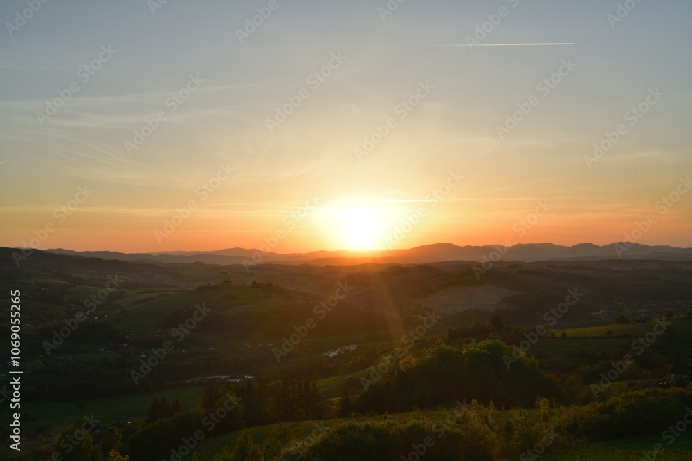 The sunset and its rays dazzle the green forests and meadows
