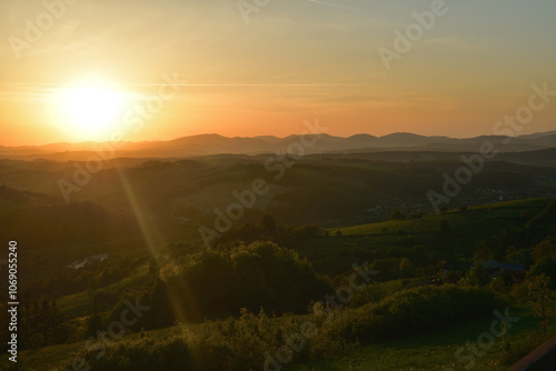 Obraz na płótnie The sunset and its rays dazzle the green forests and meadows w salonie