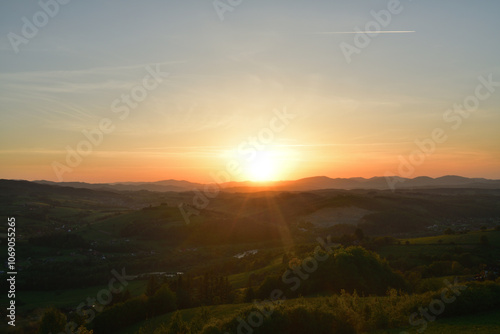 Obraz na płótnie The sunset and its rays dazzle the green forests and meadows w salonie