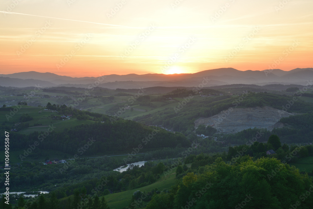 The orange sunset and its rays dazzle the green forests and meadows The orange sunset and its rays dazzle the green forests and meadows
