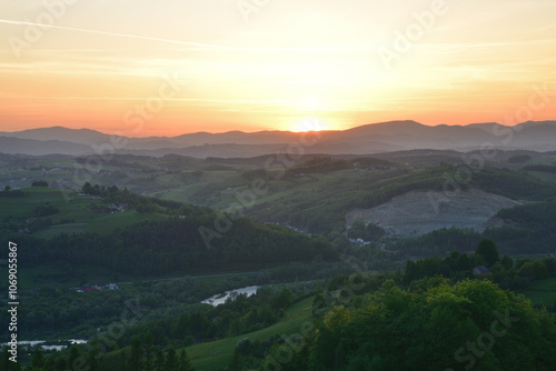 The orange sunset and its rays dazzle the green forests and meadows photo