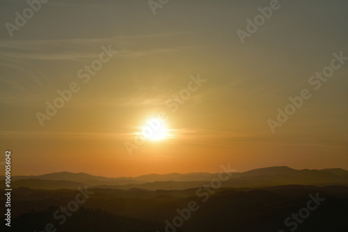 Obraz na płótnie The orange sunset and its rays dazzle the green forests and meadows w salonie