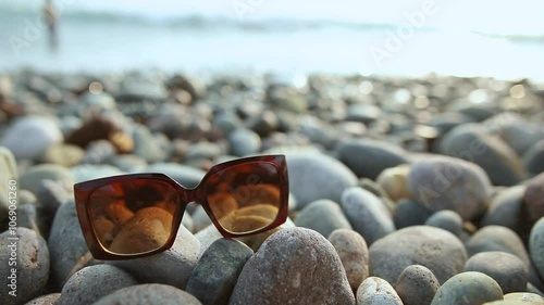 A pair of sunglasses are lying on a rocky beach