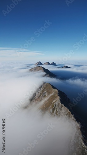 Wallpaper Mural A breathtaking aerial view of rugged mountains shrouded in mist, creating a serene and mystical atmosphere against a vibrant blue sky. Torontodigital.ca