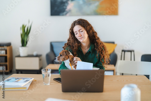 Young woman working at her desk with her dog on her lap in a casual workspace photo