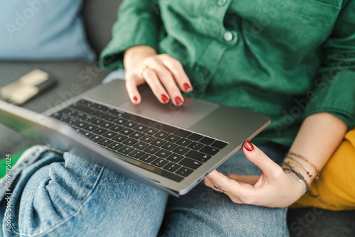 Close-up of a woman's hands with red nails typing on a laptop keyboard photo