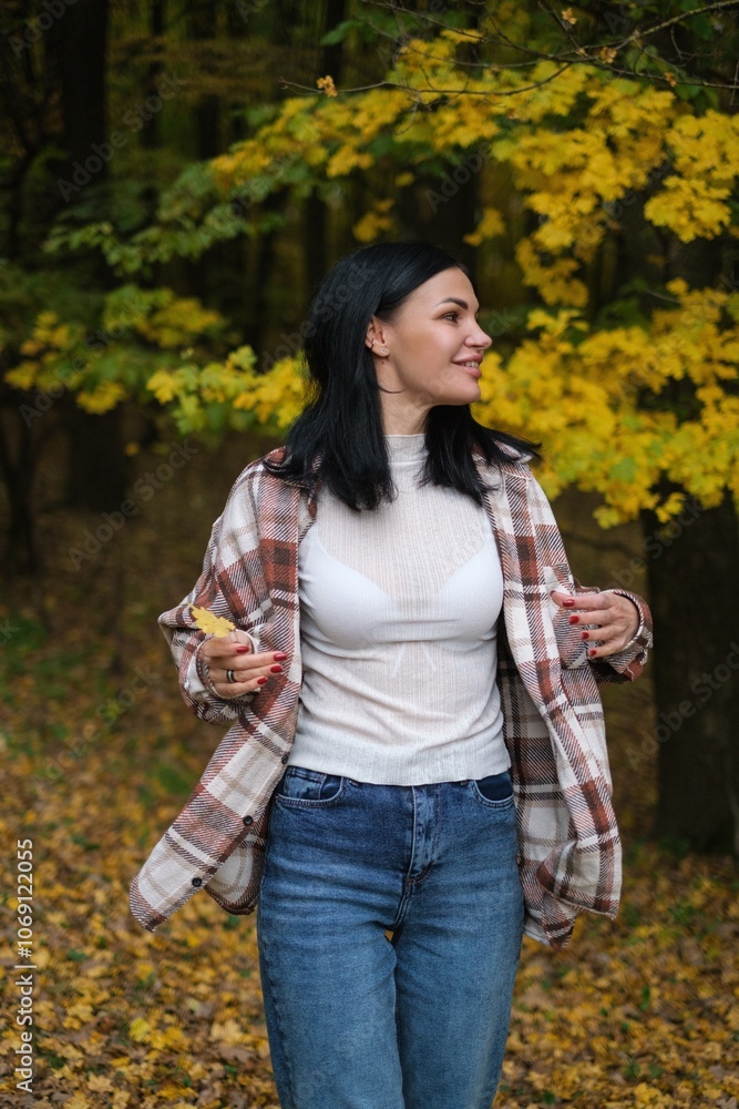 Young woman with dark hair in a plaid shirt holding a yellow leaf in an autumn forest. Captures the beauty of fall, nature, and outdoor lifestyle. Perfect for seasonal or nature-themed visuals. Young woman with dark hair in a plaid shirt holding a yellow leaf in an autumn forest. Captures the beauty of fall, nature, and outdoor lifestyle. Perfect for seasonal or nature-themed visuals.