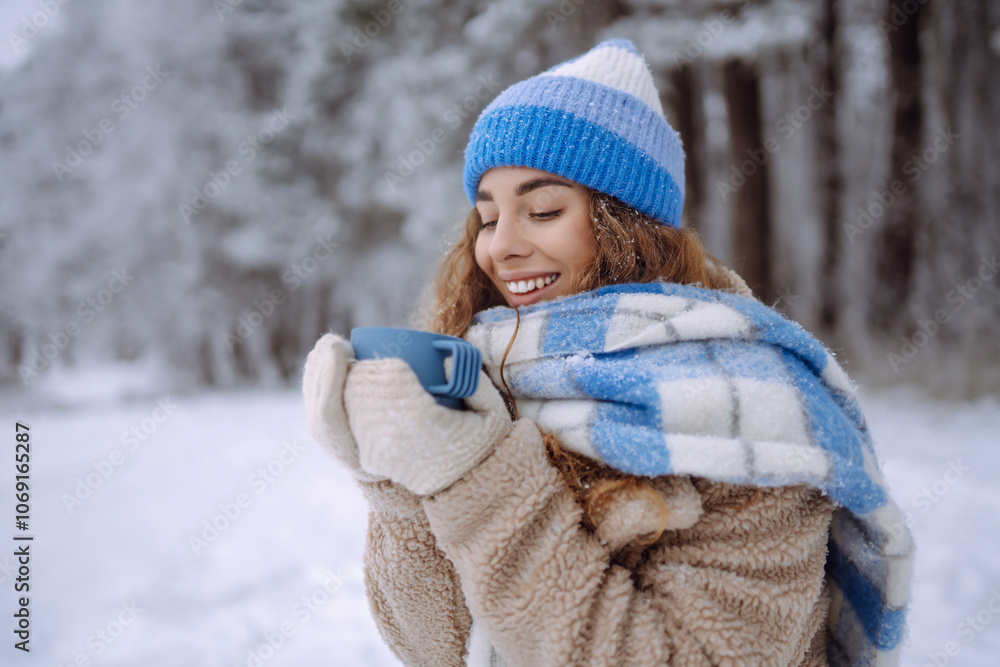 Beautiful woman is drinking a hot drink from a cup in the winter in nature. Winter forest. Travel, tourism, nature, active lifestyle. Beautiful woman is drinking a hot drink from a cup in the winter in nature. Winter forest. Travel, tourism, nature, active lifestyle.